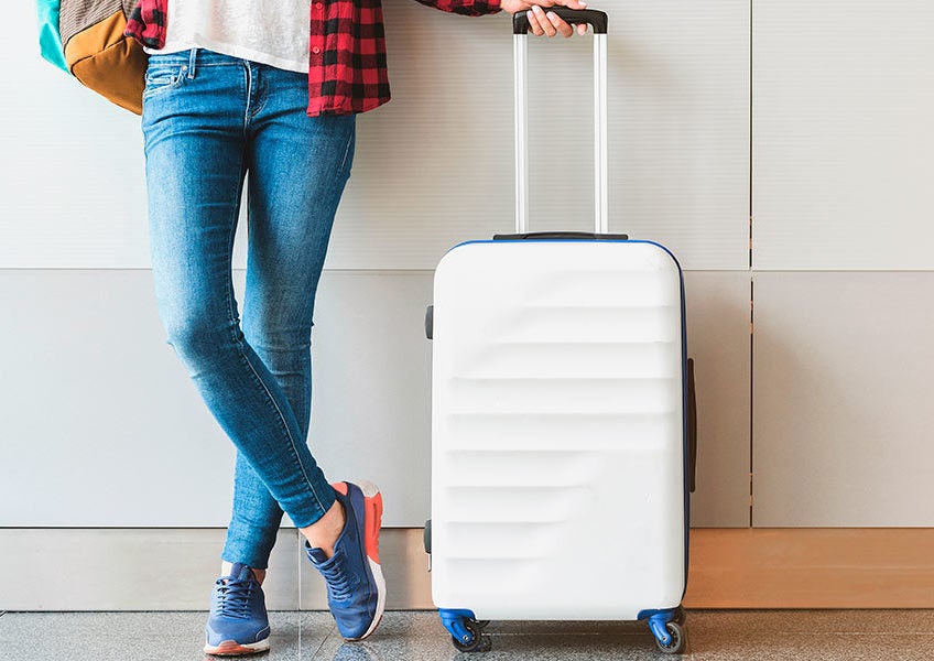 A woman standing next to a suitcase